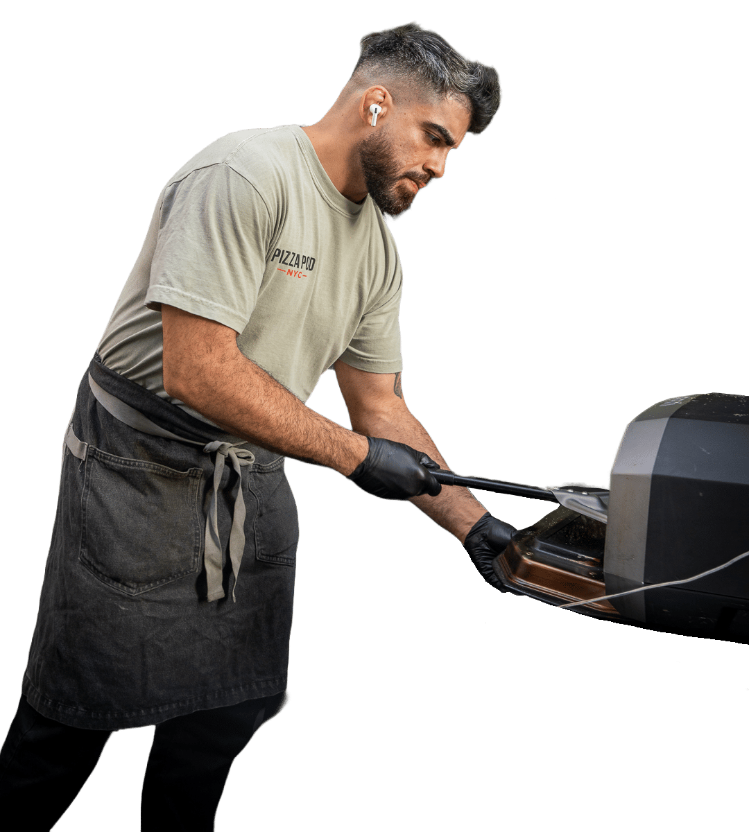 Bradley Alvelo in a Pizza Pod NYC shirt and apron, sliding a pie into the oven with a peel.
