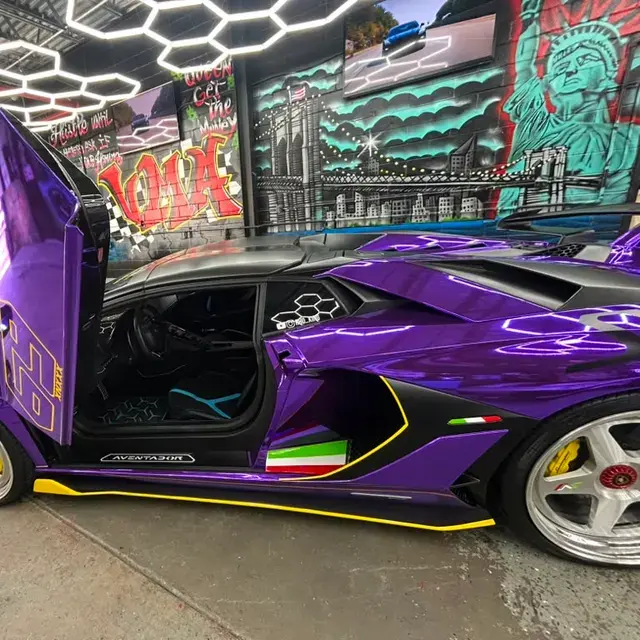 A purple supercar with its scissor door raised, parked in the same mural-covered garage