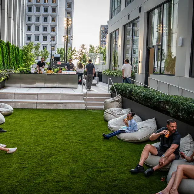 Guests lounging on beanbags on the rooftop lawn, the party carrying on at the far end under the towers